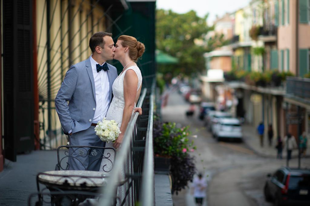 New Orleans couple kissing on a wrought-iron balcony overlooking a bustling street